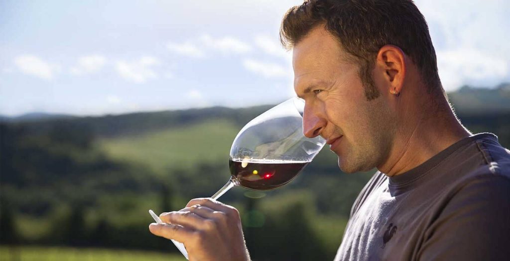Vigneron du Domaine Erta di Radda dégustant un verre de vin rouge, illustrant la passion et le savoir-faire viticole en Toscane.